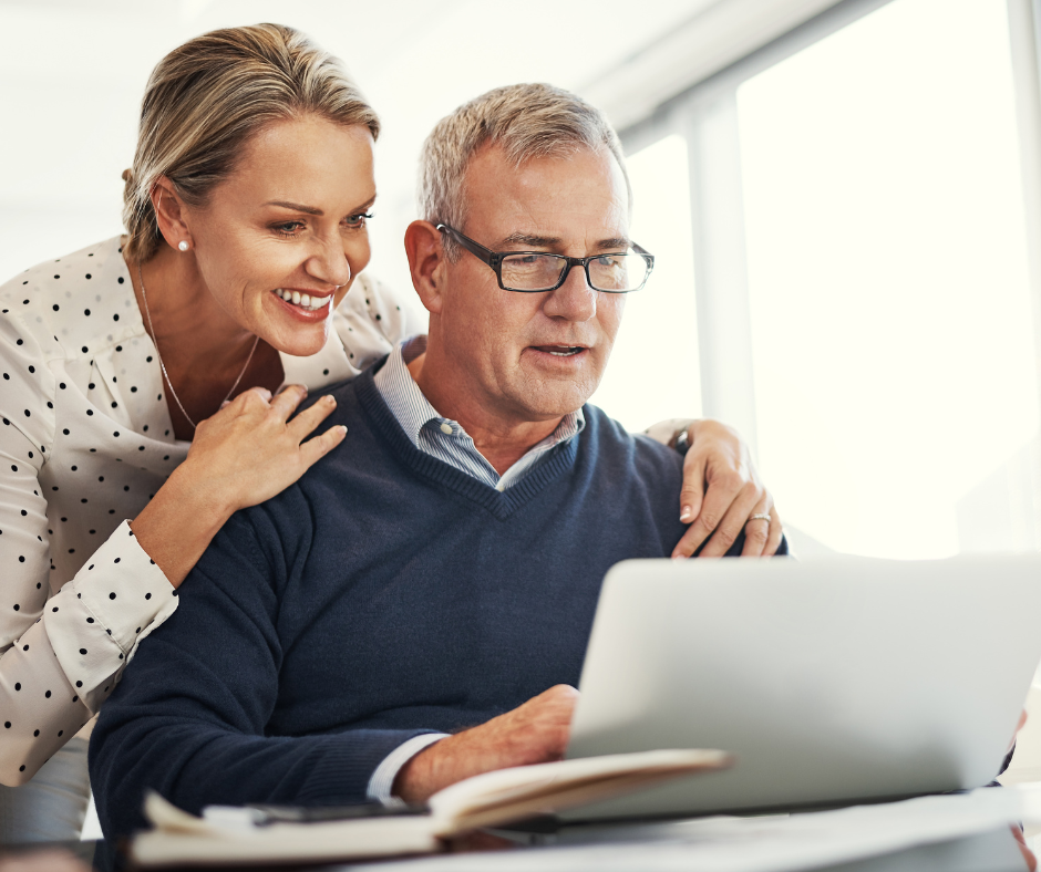 a man and woman sat at a laptop smiling