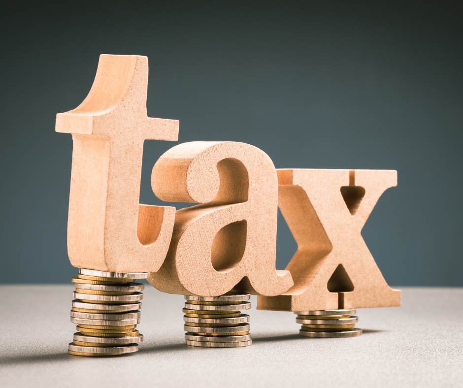 wooden blocks spelling the word 'Tax' balancing on piles of coins