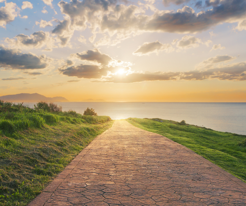 a singular pathway leading towards an ocean landscape at sunruse