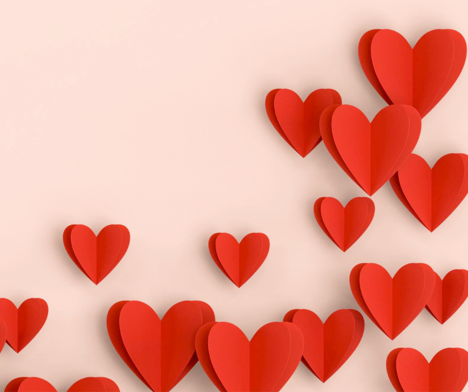 a selection of red paper hearts arranged on a pale pink background