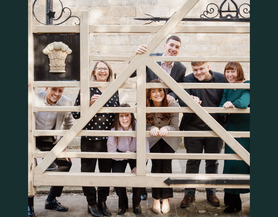 the stephen eve team, danielle, ben, mandy, rav, ryan, ali, and sally pose for a fun photo, peeking between the gaps of the gates of nottingham park estate
